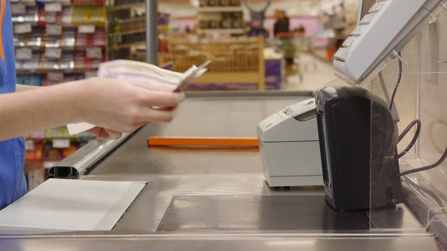 cashier counts money in supermarket