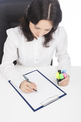 businesswoman wearing white writing on paper sheet while sitting