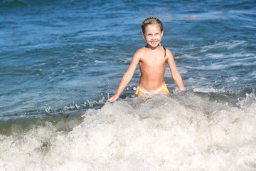 Little girl crying in the spray of waves at sea