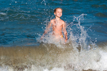 Little girl crying in the spray of waves at sea