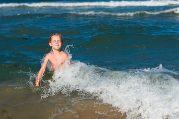 Little girl crying in the spray of waves at sea