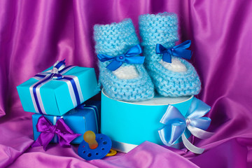blue baby boots, pacifier, gifts on silk background.