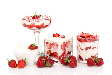 Glasses of ripe strawberries with cream isolated on white