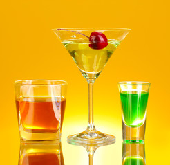 a variety of alcoholic drinks on yellow background