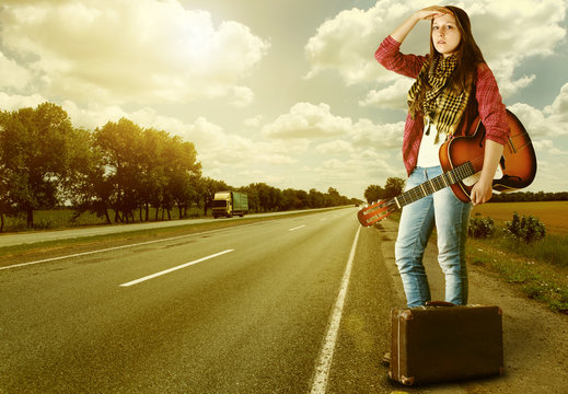 Yong Girl  with guitare and old suitcase at the highway