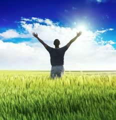 Fototapeta na wymiar Człowiek stojący na zielonym polu pod błękitne niebo