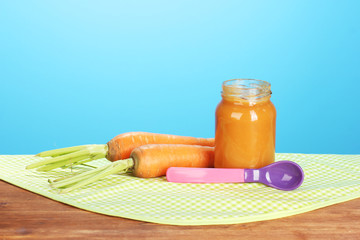 Jar with carrot baby food, spoon and carrots