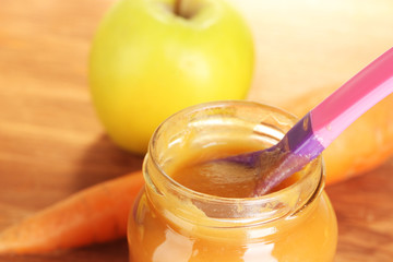 Jar with carrot and apple baby food, spoon and carrot and apple