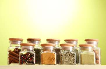 powder spices in glass jars on green background