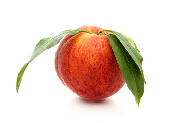 Ripe peach with green leaves.
