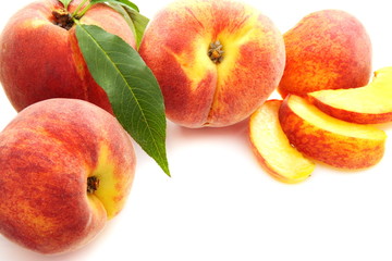 Fruits of peach with green leaves.
