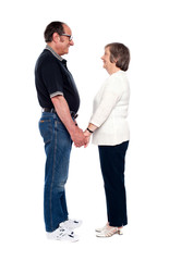 Aged couple looking at each other, holding hands