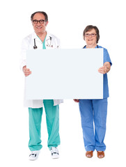 Aged doctors displaying white billboard