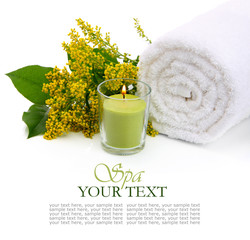 Spa setting with rolled towel, flowers and burning candle