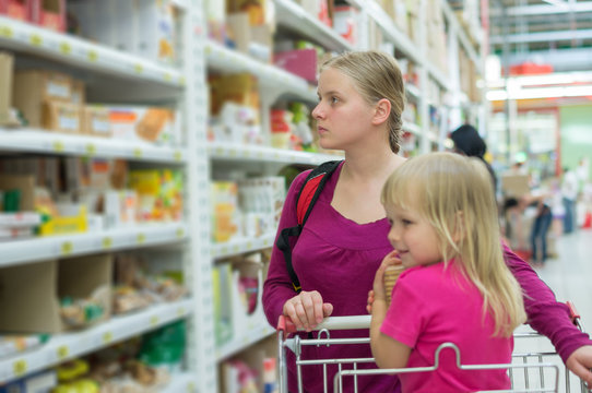 Mother and daughter shopping in cookies section in supermarket
