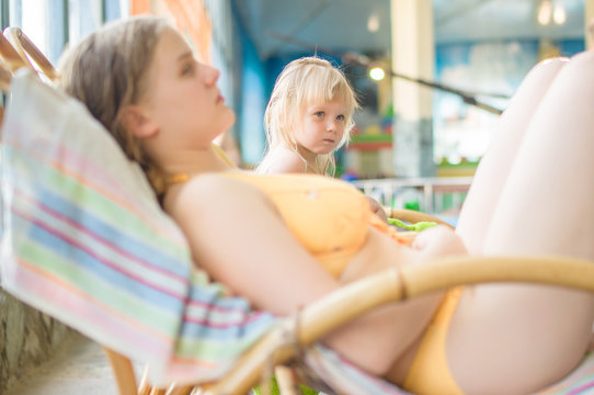 Young mother with adorable daughter relax on chairs in aqua perk