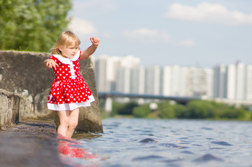 Naklejka premium Adorable girl stay in water on pier ladder