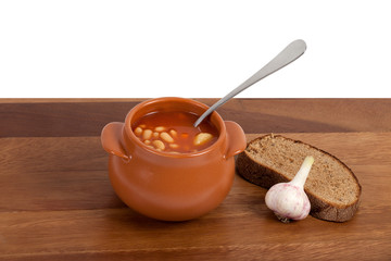 Soup in ceramic pot with bread and garlic