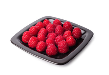 Raspberries on a black plate isolated on white background