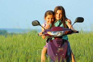 two young girls playing outdoor on scooter