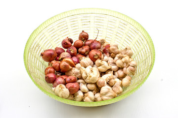 Shallots and garlic in a green basket isolated on white.