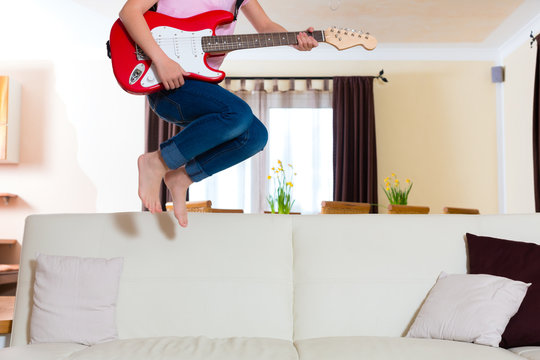 Child Jumping With Guitar On The Couch