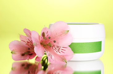 Jar of cream with flower on green background