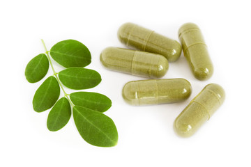 Moringa oleifera capsule with green fresh leaves on white backgr