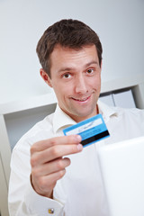 Mann mit Kreditkarte vor Laptop
