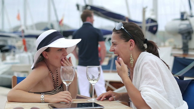 Two women looking at handsome man at marina, steadycam shot
