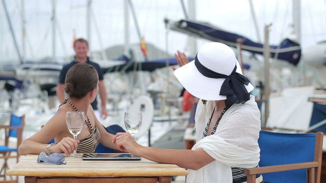 Two women meet handsome man at marina, steadycam shot