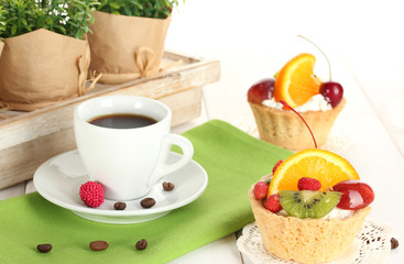 cup of coffee and sweet cakes with fruits on wooden table