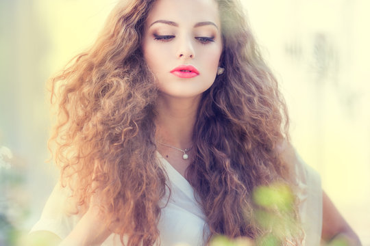 Beautiful young woman with gorgeous curly hair outdoors