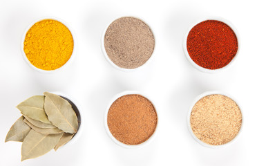  Different spices in white bowls isolated on white background.