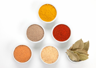  Different spices in white bowls isolated on white background.