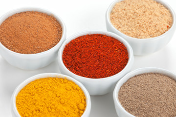  Different spices in white bowls isolated on white background.