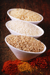Three bowls with different types of rice and indian spices