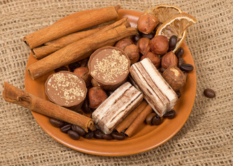 Sweets, cinnamon, nuts and coffee beans on a saucer, on burlap b