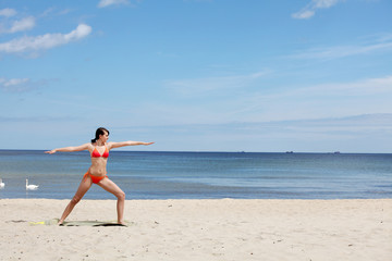 Athletic young woman is training exercises on the beach.