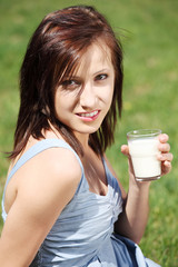 Young woman with smile drinking milk in hot day