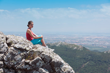 Young athletic girl relaxing on top of rocks