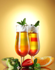 fruit jelly in glasses and fruits on yellow background