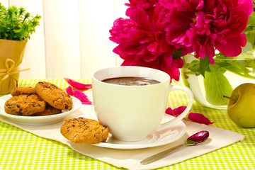 cup hot chocolate, apple, cookies and flowers on table in cafe