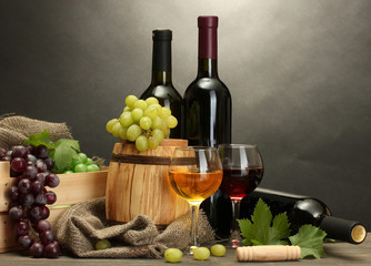 barrel, bottles and glasses of wine and ripe grapes