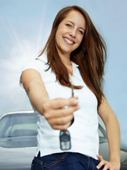 Pretty woman proudly presents the key of her car outdoors