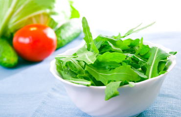 Green rucola fresh salad in white bowl