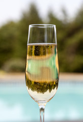 Flute of cold champagne by side of pool
