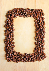 Coffee beans as frame with old paper for notes on the wooden bac