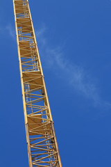 Fototapeta na wymiar Yellow hoisting crane on blue sky background