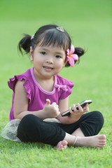 Little baby girl with mobile phone on grass